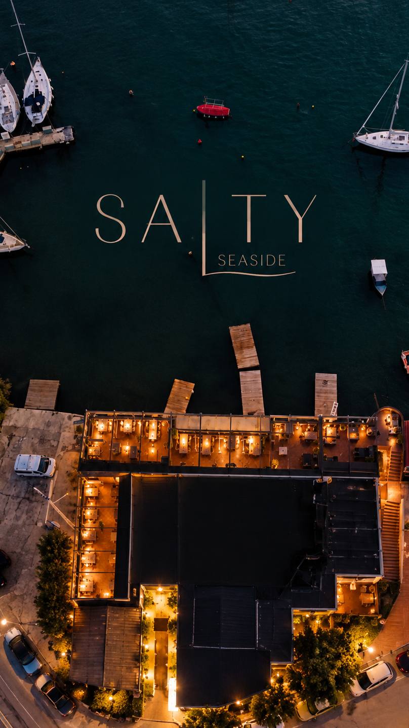 Αεροφωτογραφία του SALTY Seaside στο Μικρολίμανο τη νύχτα, με φωτισμένη βεράντα και σκάφη στη μαρίνα, Πειραιάς
